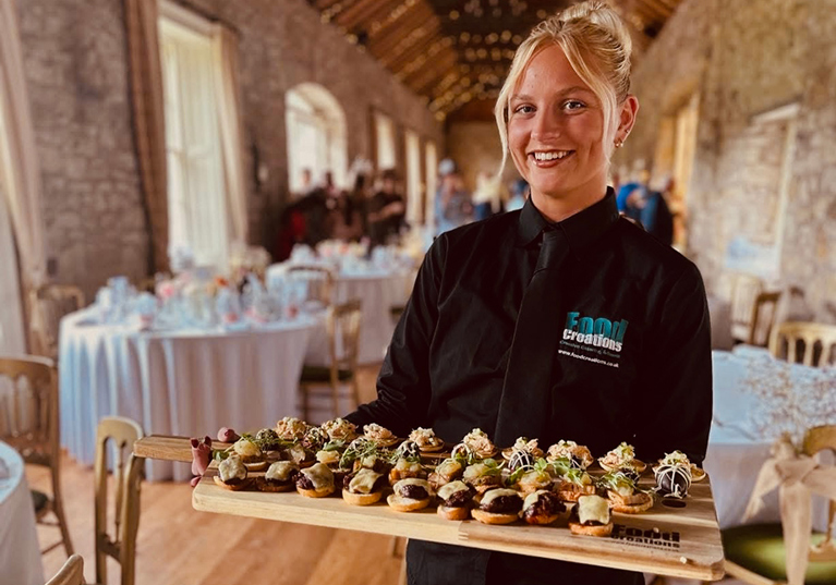 Food Creations server holding a tray of canapés at a barn wedding reception