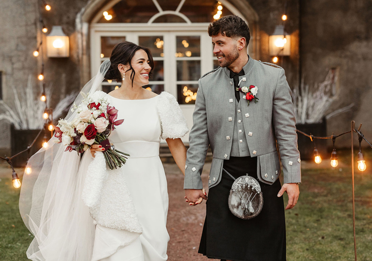 Bride and groom smile as they walk away from Gordon Castle.