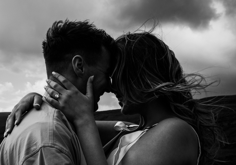 Bride embraces grooms face in black and white.