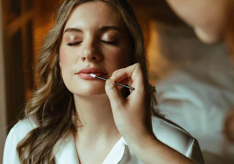 Professional image of bride with eyes closed having lipstick put on by MUA Jill Rowan Makeup