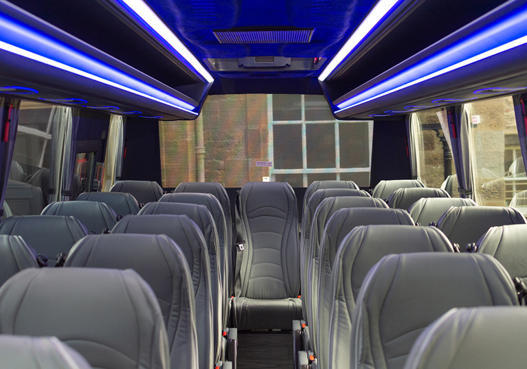 Inside one of Anderson Black Executive Travel's modern buses, with grey leather seats and blue overhead lighting
