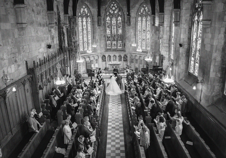 Overhead black and white view of a church wedding ceremony planned by DSW Weddings, with guests seated in wooden pews