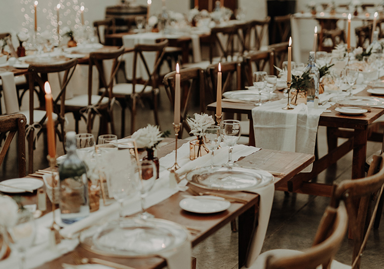 Rustic long-table wedding styling with wooden chairs, candlelight and neutral linen decor at a Scottish barn reception