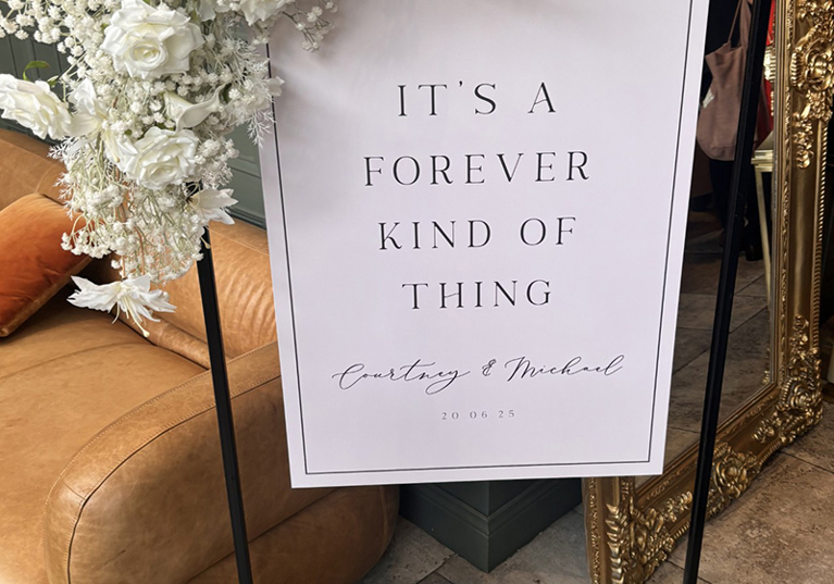 Modern wedding welcome sign on black stand with white florals and candles, personalised for Courtney and Michael