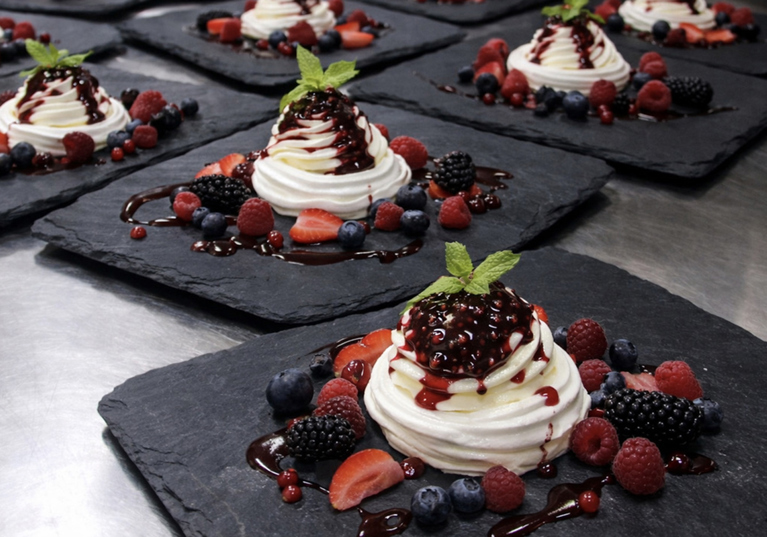 Scottish wedding dessert of meringue topped with fresh berries and berry coulis on slate plates by The Tasty Hog Company