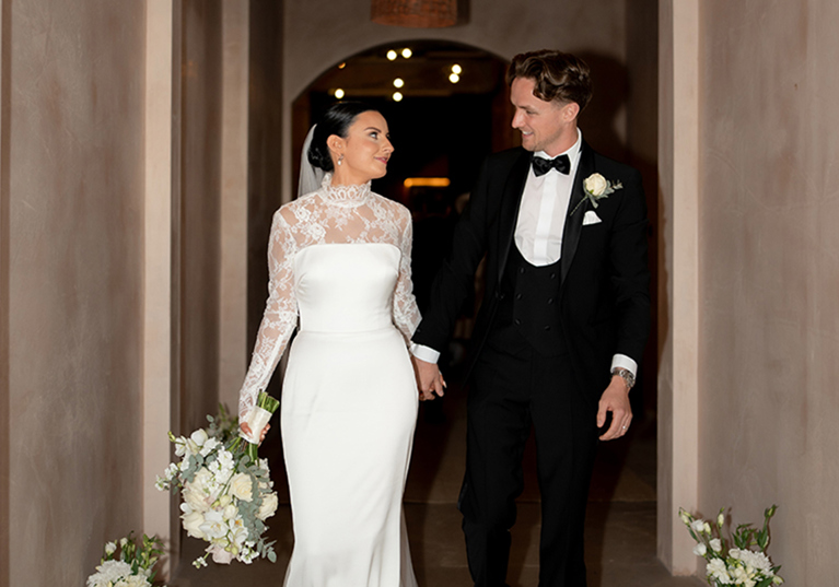 Bride and groom walking hand in hand through archway at stylish city wedding venue