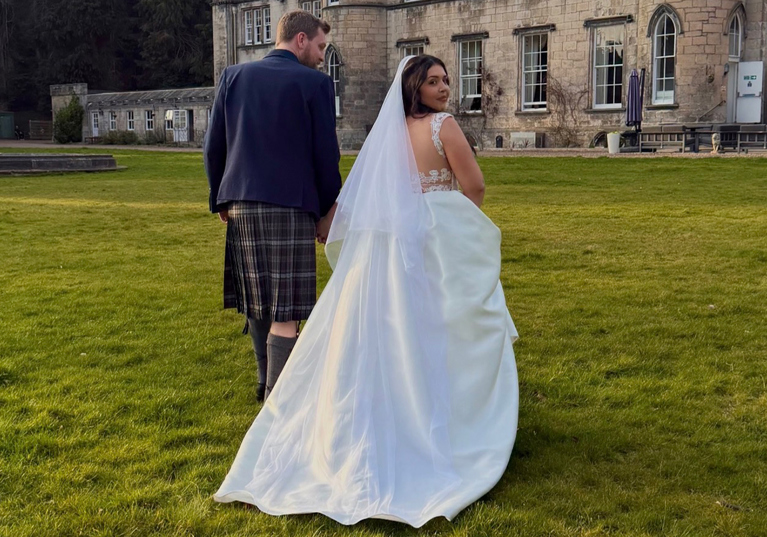 Bride and groom walking across the grounds of a Scottish castle wedding venue captured by Arauthentic Moments