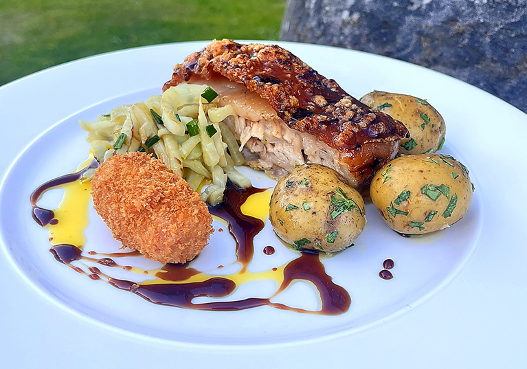 Plated pork dish with potatoes, vegetables and croquette served by Wylie & Wood as part of a luxury catering menu.