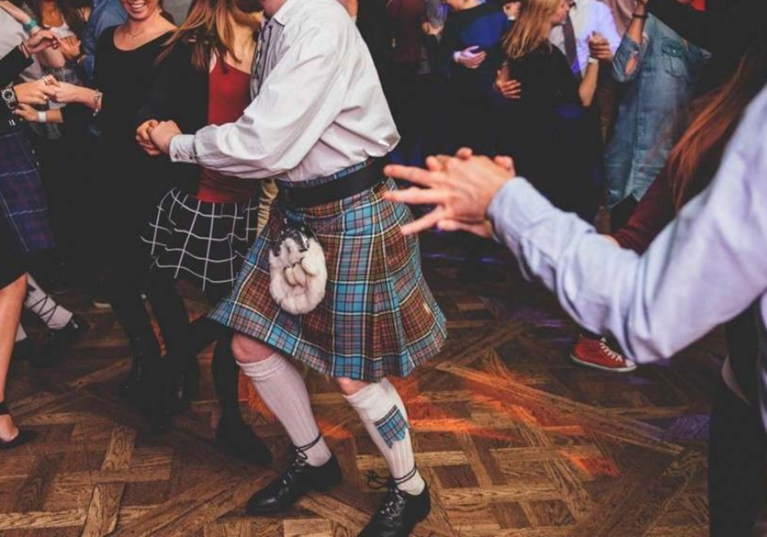 Guests dancing together on a lively Scottish wedding dance floor during evening celebrations.