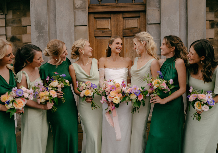 Bride and bridesmaids in green dresses holding colourful bouquets by Agapanthus Flower Studio