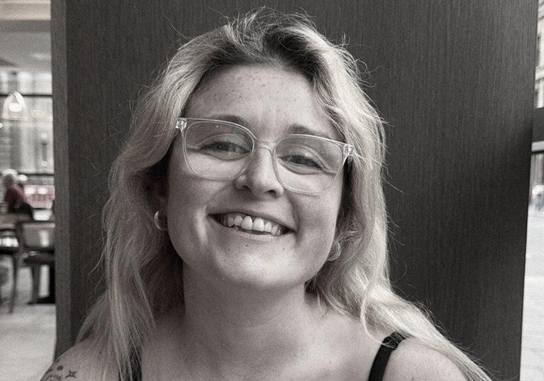 Black-and-white portrait of the smiling With Vic wedding content creator wearing glasses.