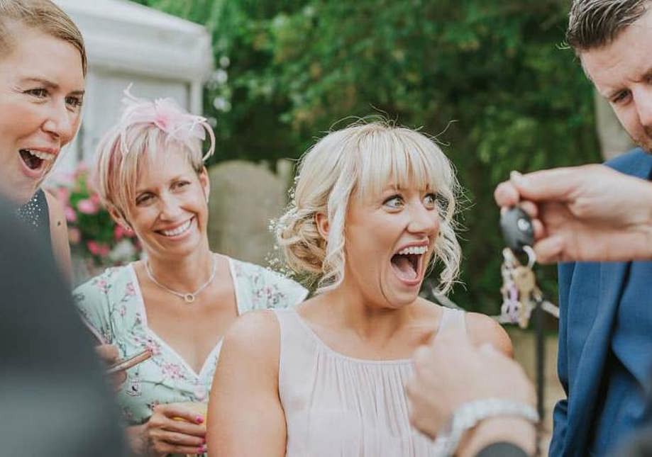 Wedding guests reacting to close-up magic at an outdoor reception