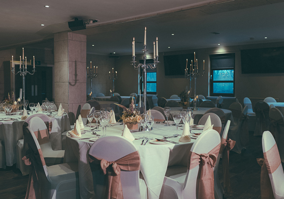 Wedding meal set up in the Crosslee Suite at The River Inn in Houston, Renfrewshire, with pink bows on chairs and silver candelabras.