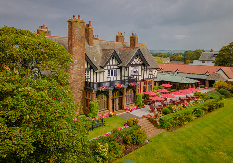 Exterior of Piersland House wedding venue with landscaped gardens, terrace seating and red parasols