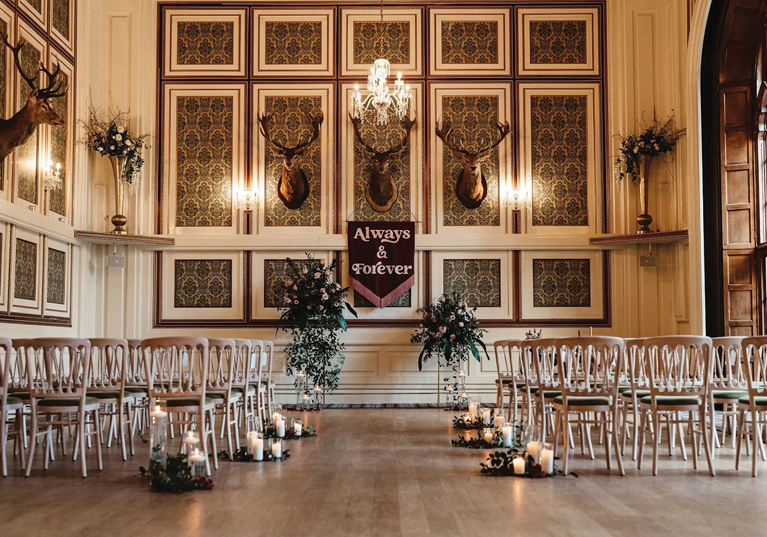 Wedding ceremony set-up in a traditional panelled room at Drumtochty Castle, featuring candles and floral arrangements.