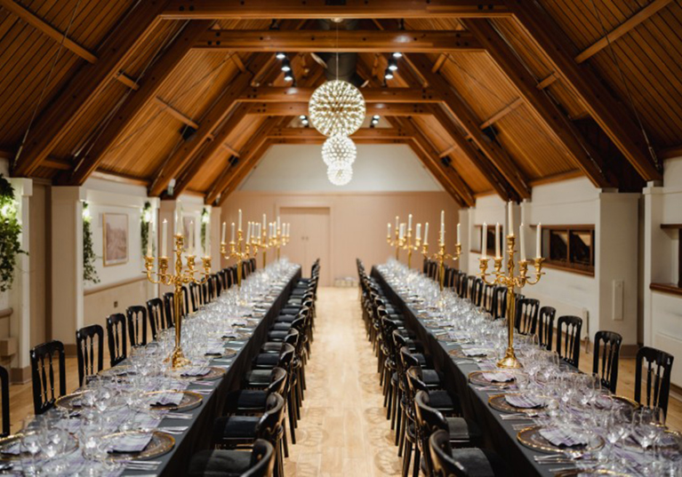 Long banquet tables styled with gold candelabras for a wedding breakfast inside Edinburgh Castle’s grand reception hall.