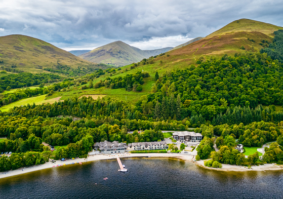 Lodge on Loch Lomond drone image showing woodlands and hills beyond the Loch Lomond wedding venue.