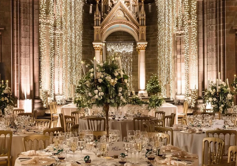Wedding reception set up inside Mansfield Traquair Edinburgh with fairy lights, gold chairs and white floral centrepieces