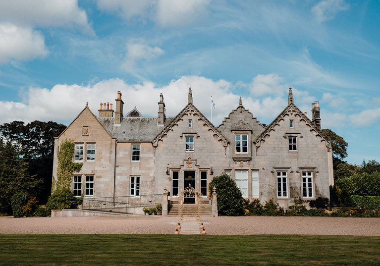 Exterior of Netherbyres House wedding venue in the Scottish Borders with blue skies and historic stone façade
