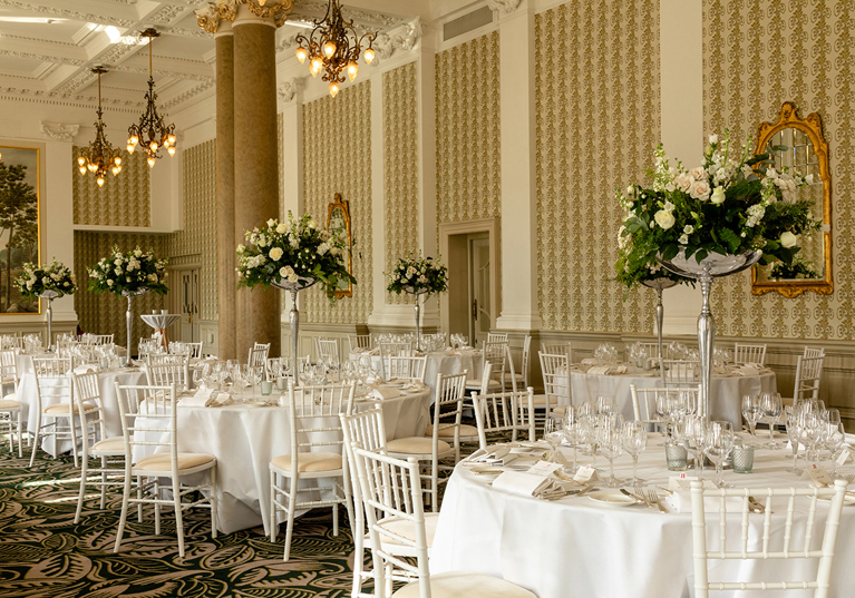 Wedding reception setup at The Balmoral Hotel Edinburgh with round tables, white Chiavari chairs and tall floral centrepieces