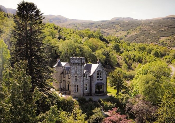 Aerial view of Castle Craigard surrounded by woodland and Scottish hills
