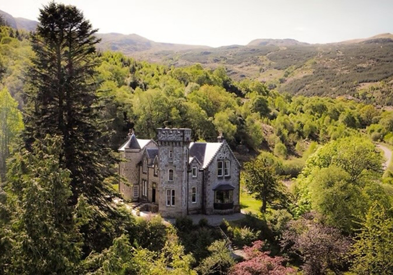 Aerial view of Castle Craigard surrounded by woodland and Scottish hills