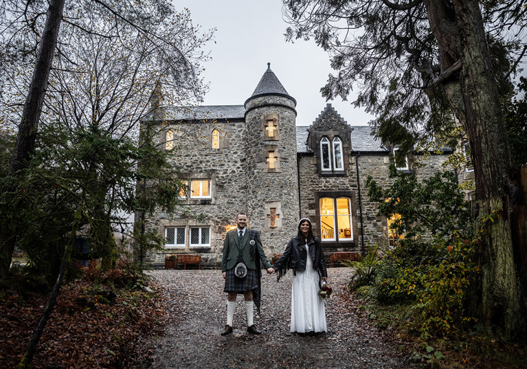 Bride and groom holding hands outside Castle Craigard stone wedding venue