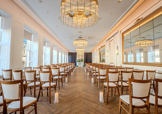 The Exchange wedding venue in Glasgow's ceremony room, with chandeliers, mirrors on walls and floral display at altar.