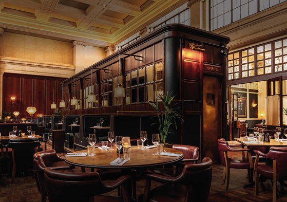 Image of the bar in food-focused venue Hawksmoor Edinburgh, with dark wood tones and warm lighting.