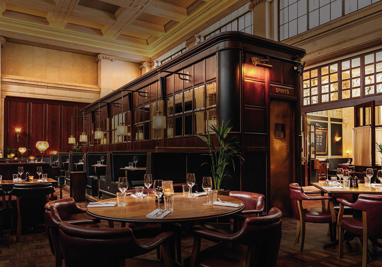 Image of the bar in food-focused venue Hawksmoor Edinburgh, with dark wood tones and warm lighting.