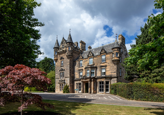 Exterior of The Scott Hotel in Edinburgh, showing its turrets with blue skies in background.