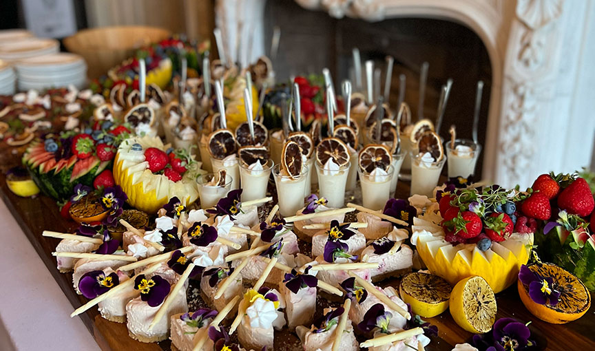 Lavish grazing table with desserts, fruit and mini puddings arranged on a wooden board by the Lunchbox Boys