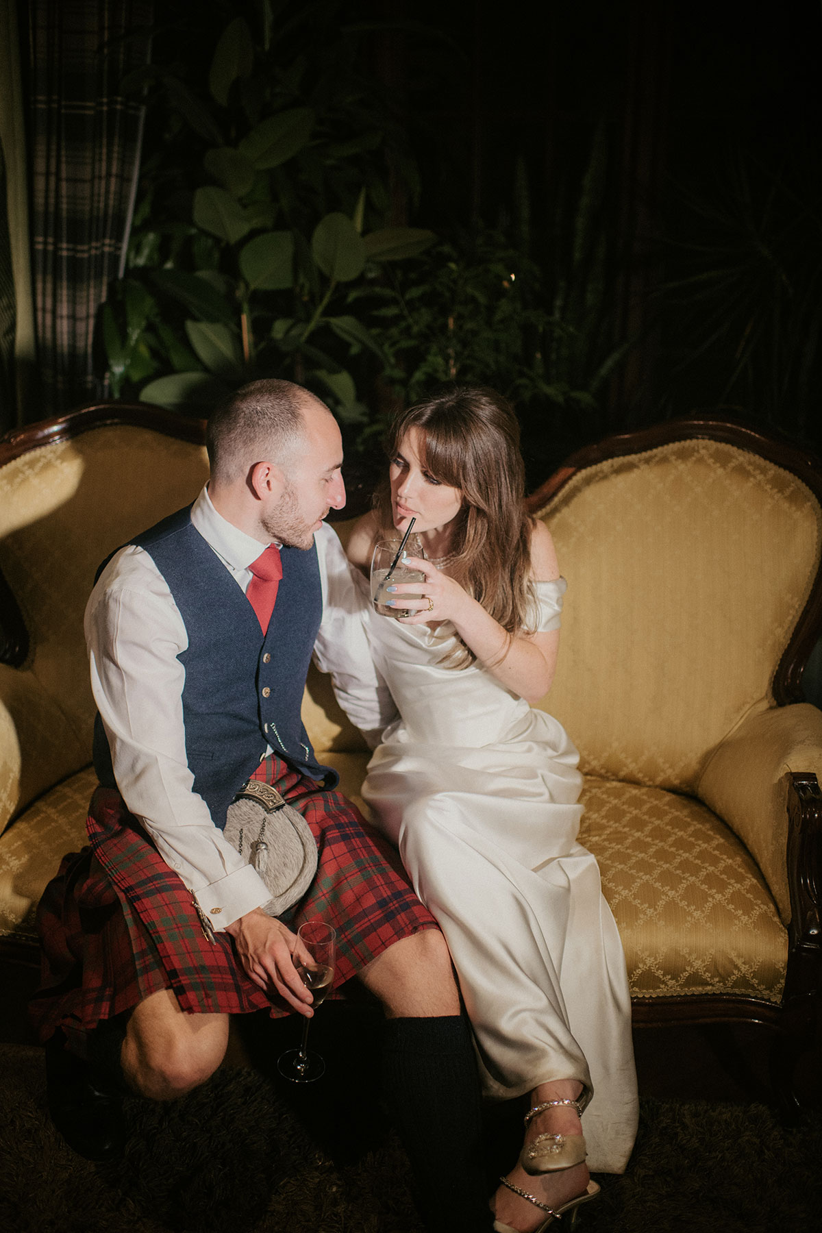 a bride and groom sitting on a chair in a dark room at Achnagairn Castle destination wedding
