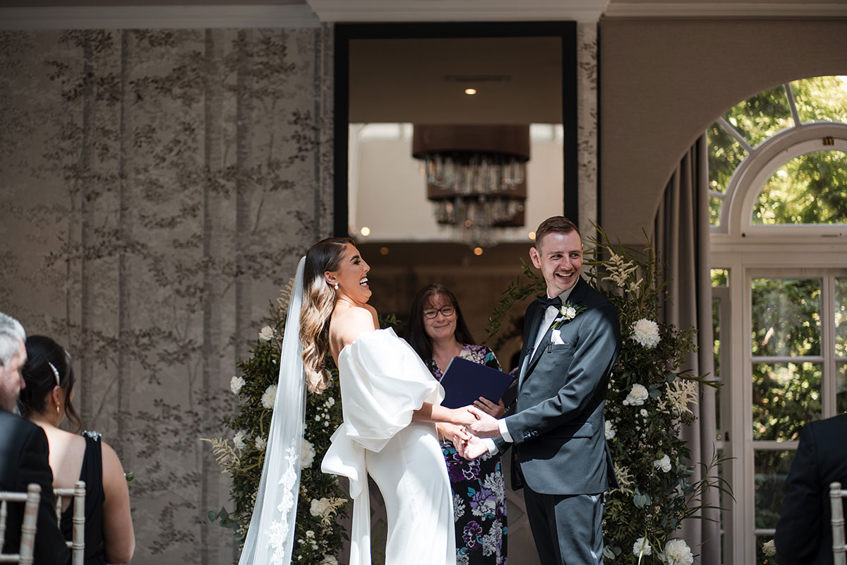 Bride and groom holding hands laughing at the altar