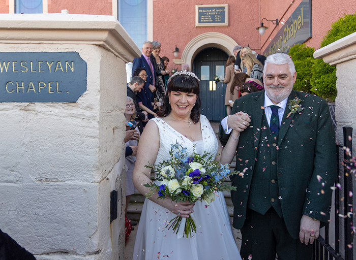 a bride and groom being showered in confetti outside the Harbour Chapel in Dunbar