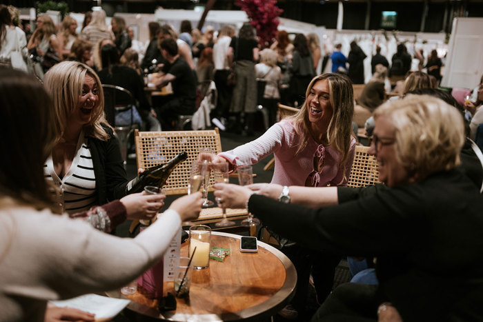 A group of women sitting at a table with drinks and a bottle in the VIP area at the Scottish Wedding Show.