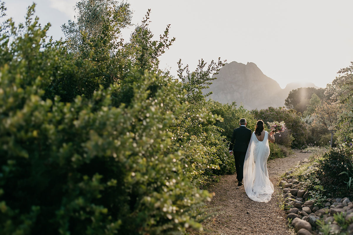 Bride and groom walking through the gardens at Boschendal Wine Estate during golden hour wedding portraits in Cape Town