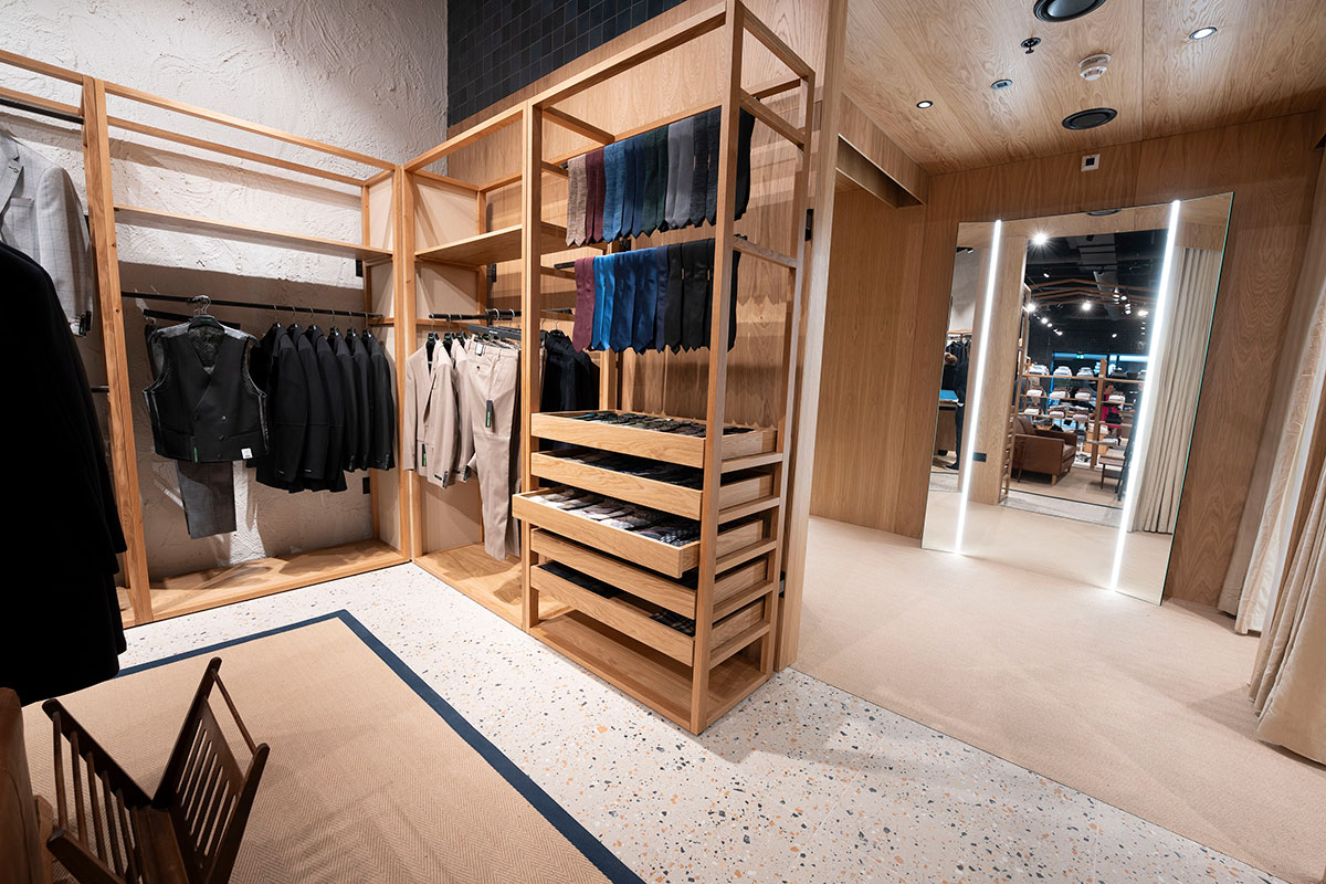 Wooden shelving with clothes and fitting room at Remus Uomo Braehead