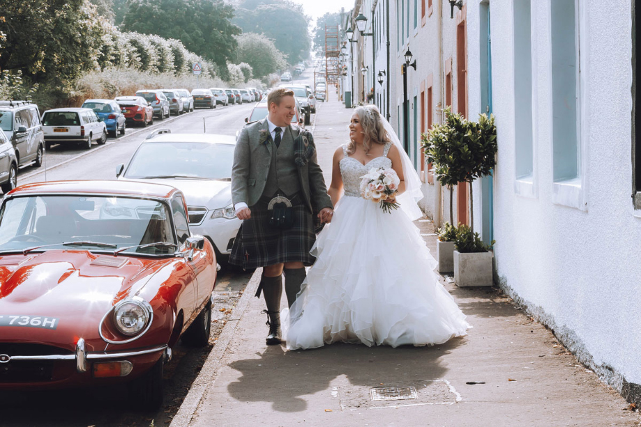 A Bride And Groom Walking Down The Street In Eaglesham