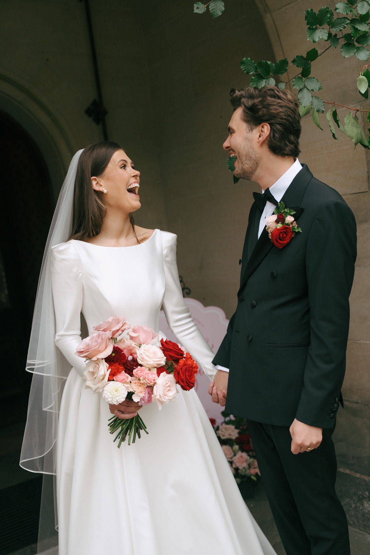 Bride Nicole and groom Ryan laugh together during their wedding portraits outside Barnbougle Castle in South Queensferry.