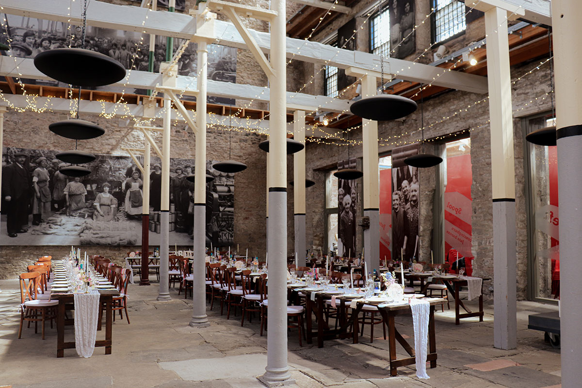 High Mill at Verdant Works Dundee set for a wedding breakfast with long tables, industrial features and festoon lighting.