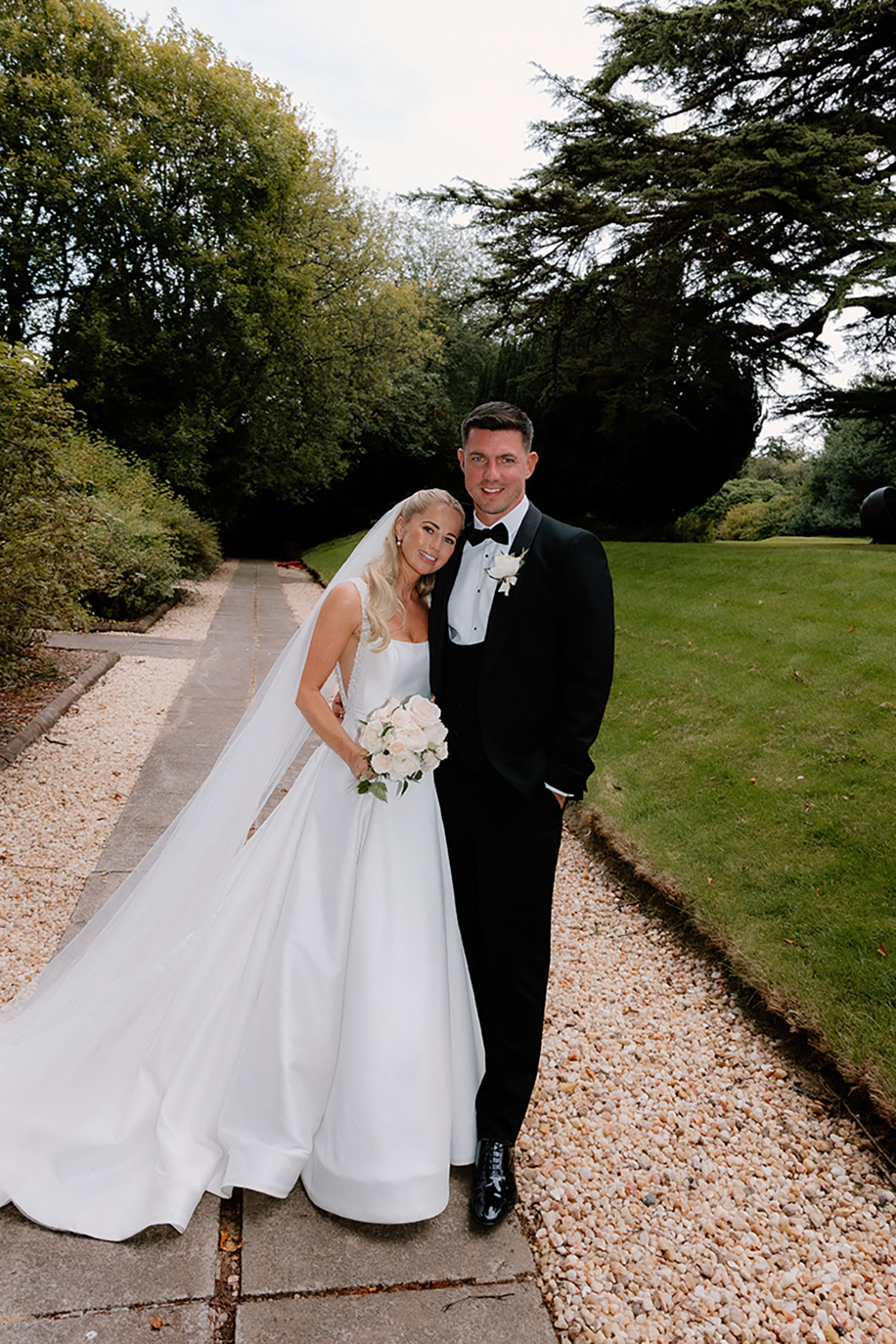 Bride and groom standing together on a garden pathway at Mar Hall, smiling at the camera.