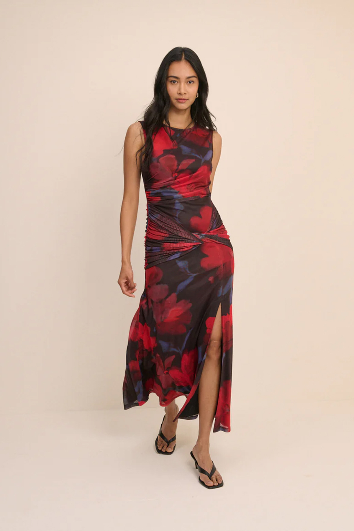 Model wearing a red and black floral mesh midi dress with ruched detailing and a thigh-high split.