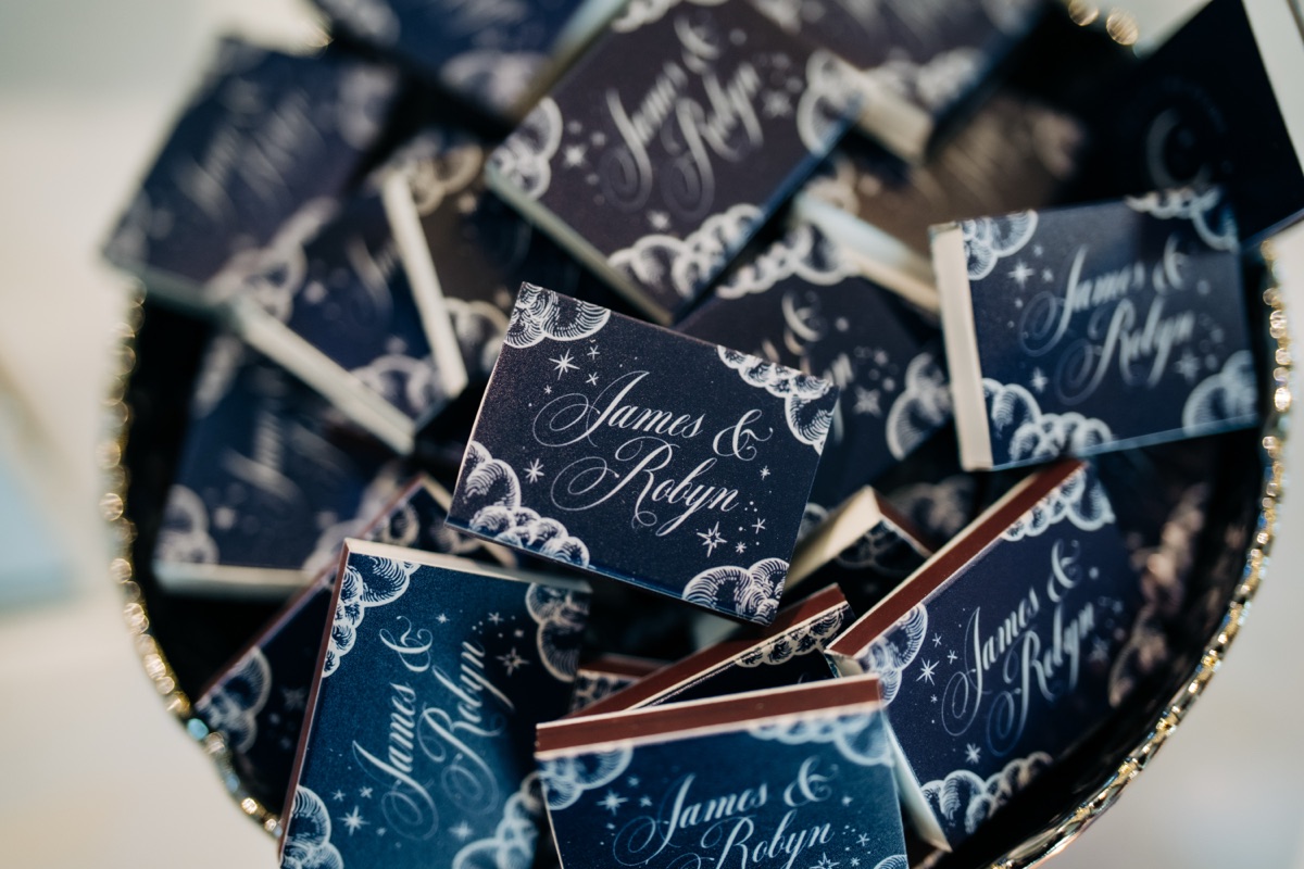 Personalised navy wedding matchboxes featuring celestial illustrations and the names James and Robyn, created for their Òran Mór wedding in Glasgow.