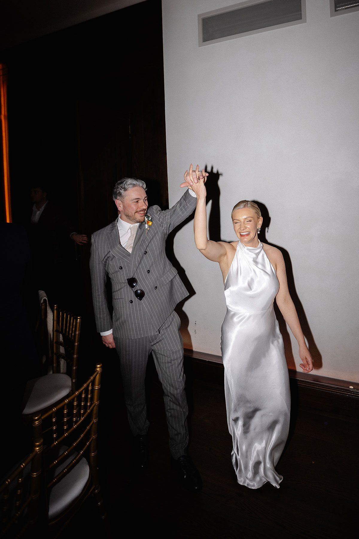 Bride and groom make their entrance at Greyfriars Hall, Virgin Hotels Edinburgh, during their evening celebration, wearing chic modern wedding attire.