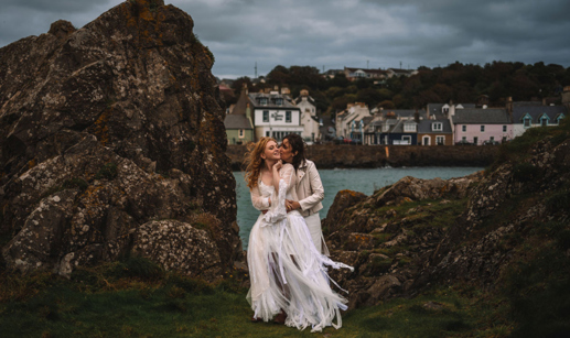 Two Brides Kissing By Rocks With Portpatrick In Background