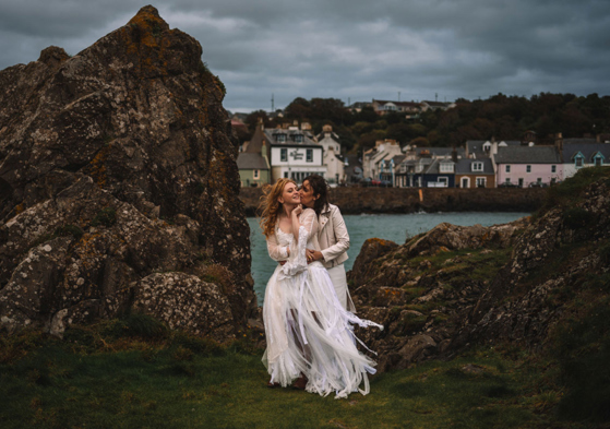 Two Brides Kissing By Rocks With Portpatrick In Background