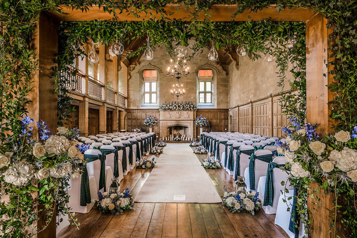 a large wooden hall with rows of chairs, tartan sashes and leaf and flower decoration.