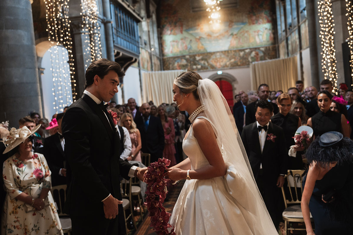 Bride and groom holding hands during Mansfield Traquair wedding ceremony surrounded by guests and fairy lights