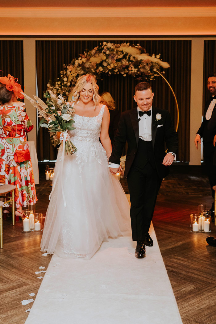 A bride and groom walking down an aisle.